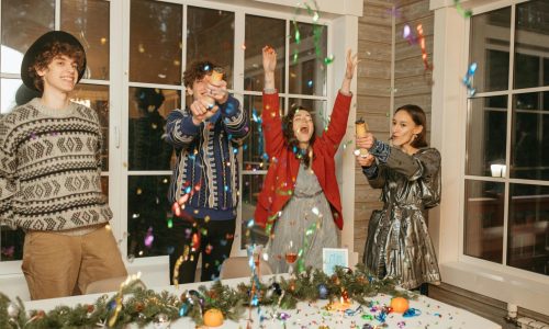 Group of young friends celebrating together with confetti indoors.